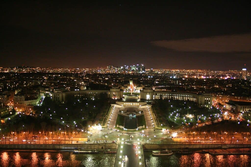 Vue nocturne de Paris depuis la Tour Eiffel, mettant en lumière la place du Trocadéro et ses jardins illuminés, avec la ville scintillante à l'arrière-plan.